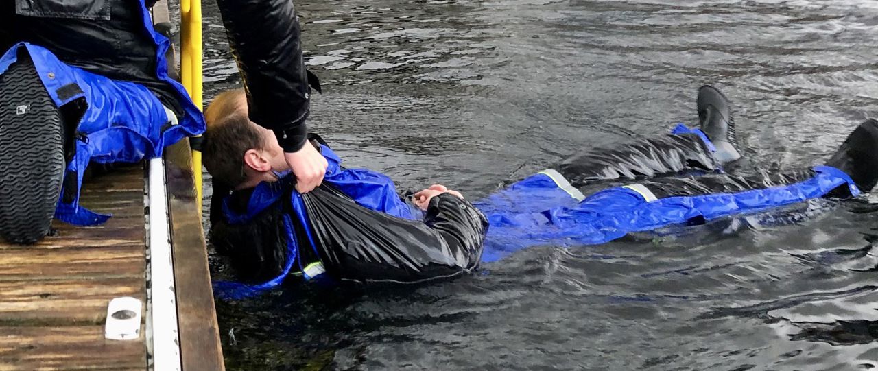 Tre personer i kjeledress på en kai 